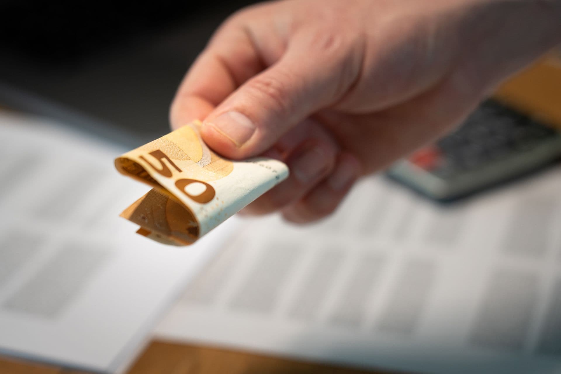 Hand die een briefje van vijftig euro overhandigt